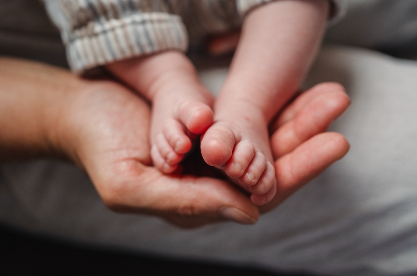 Babyfüße in den Händen der Eltern